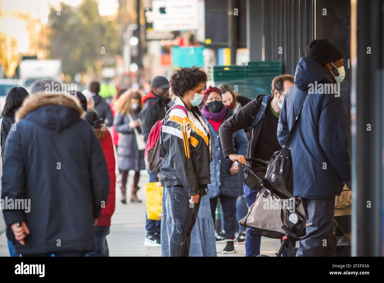 Londra, Regno Unito - 26 febbraio 2021 - clienti con maschere facciali in coda fuori dal negozio durante la pandemia COVID-19 Foto Stock