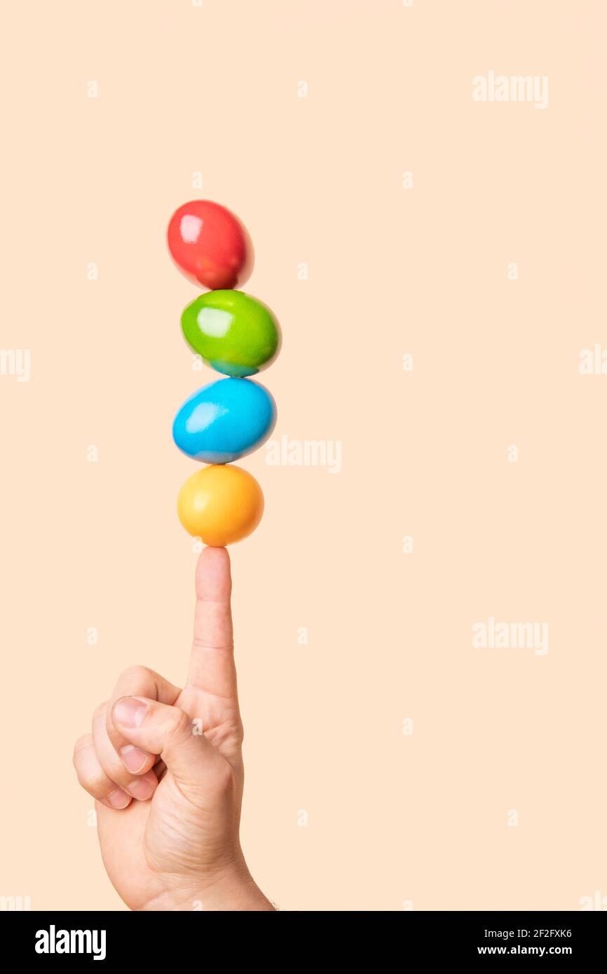 Quattro uova colorate sulla parte superiore del dito. Divertente concetto di pasqua divertente con colori e spazio di copia, minimal Foto Stock