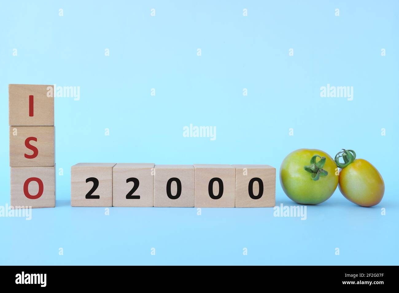 ISO 22000 o sistema di gestione della sicurezza alimentare su blocchi di legno su sfondo blu. Foto Stock