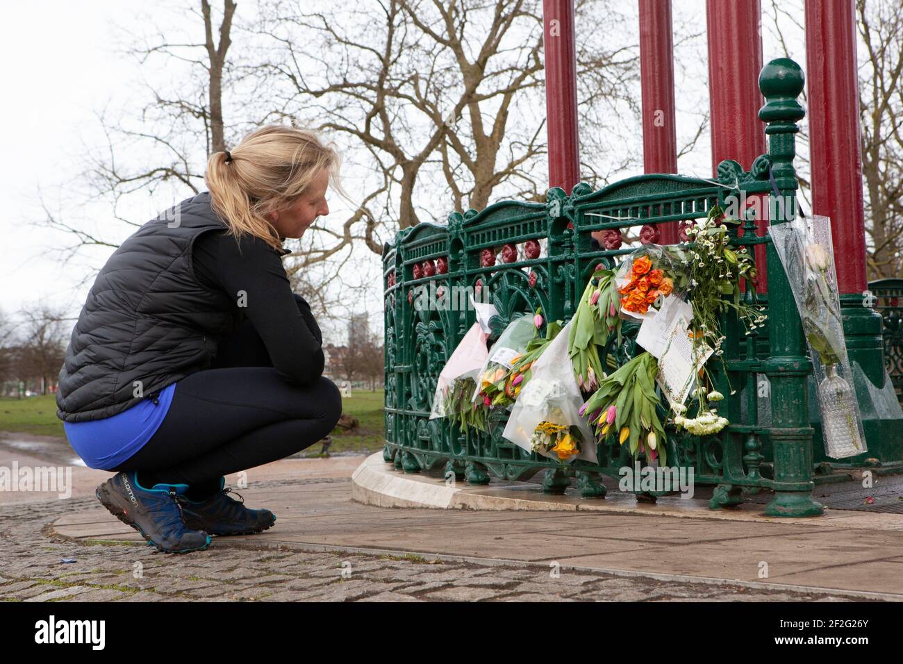 Londra, Regno Unito, 12 marzo 2021: Una donna guarda i fiori e le lettere lasciati in omaggio alla donna assassinata Sarah Everard al chiosco Clapham Common, il sito di una veglia proposta sabato 13 marzo. Anna Watson/Alamy Live News Foto Stock