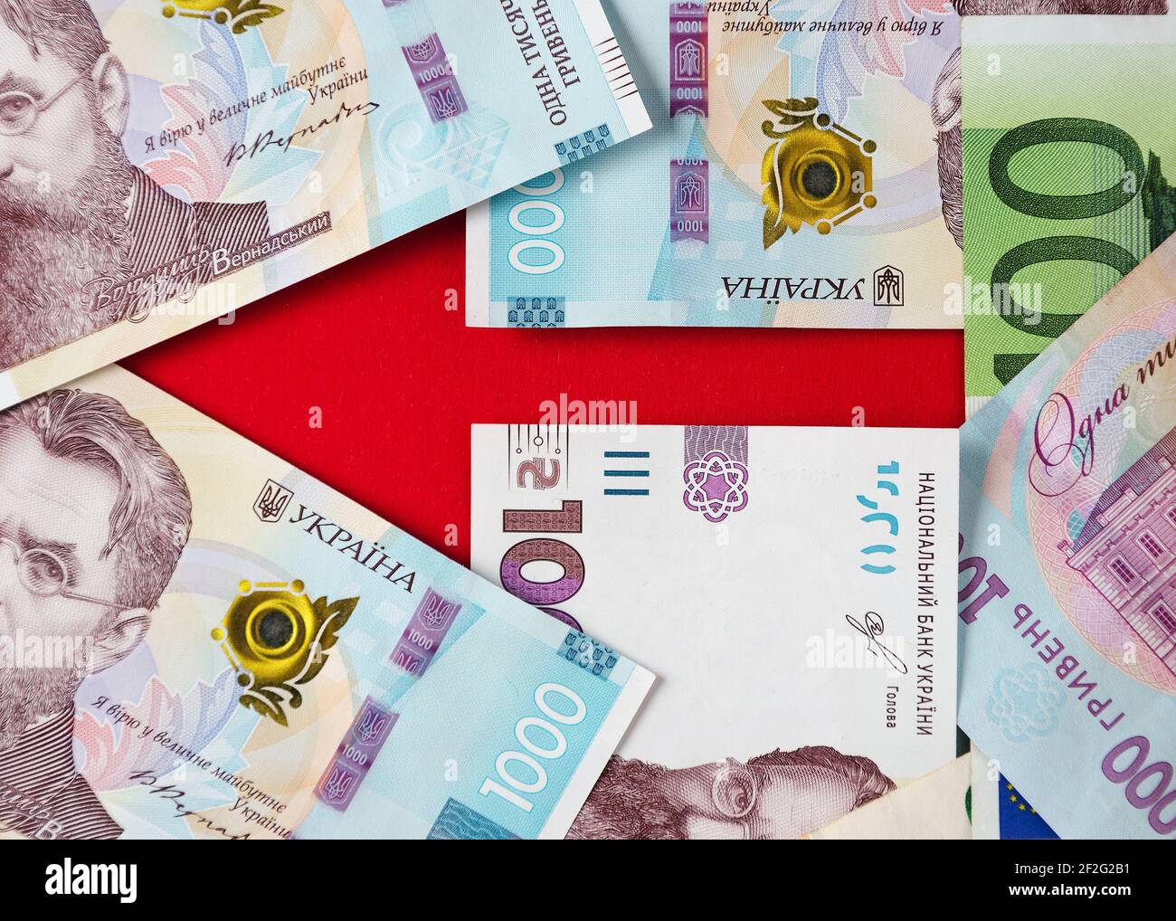 Una freccia fiancheggiata da banconote di hryvnias ucraino ed euro 5 Foto Stock