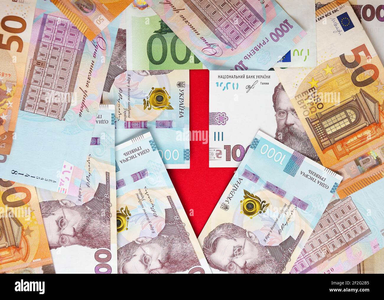 Una freccia fiancheggiata da banconote di hryvnias ucraino ed euro 6 Foto Stock