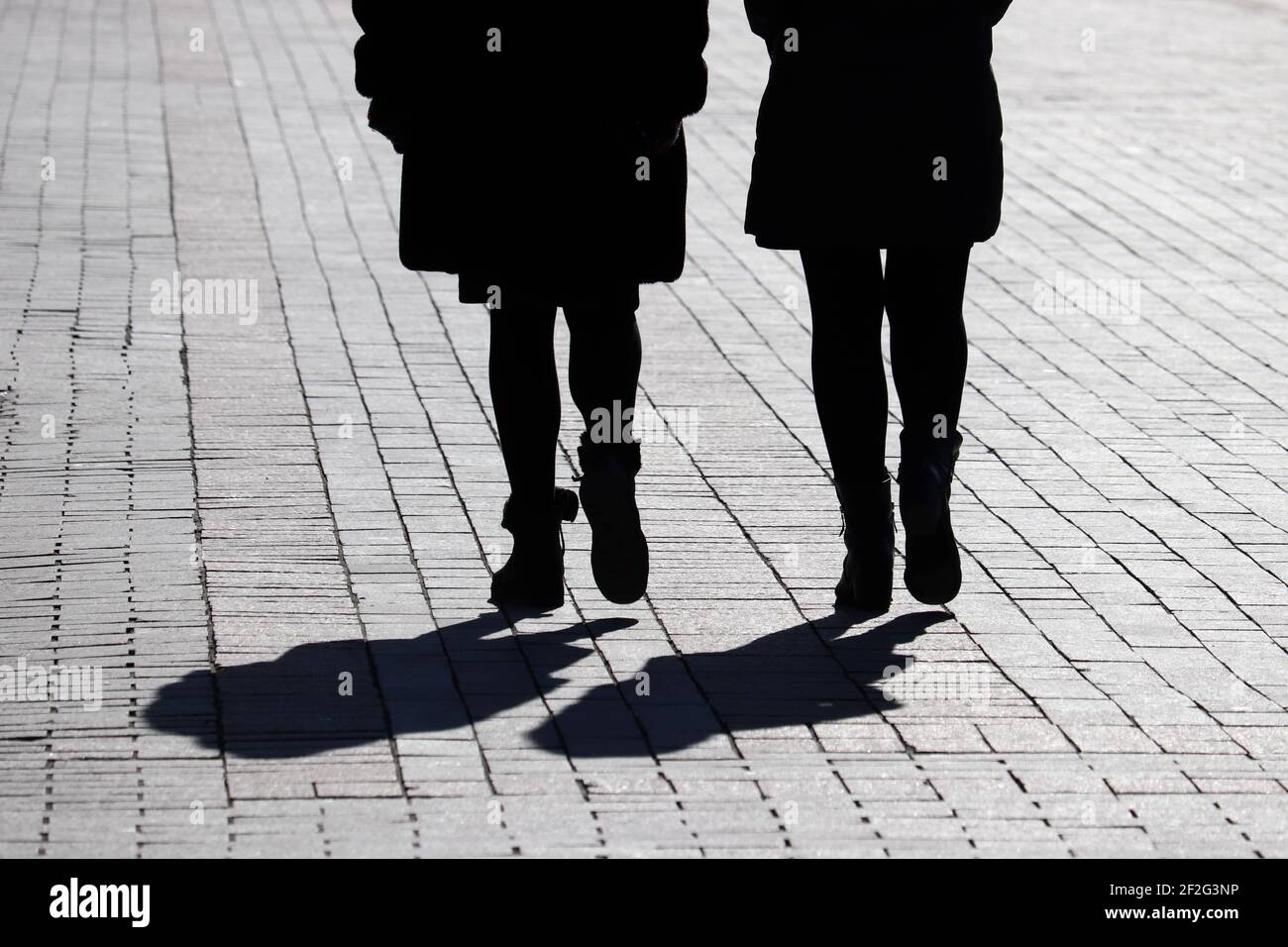 Silhouette e ombre di due donne che camminano lungo la strada. Concetto di amicizia femminile Foto Stock