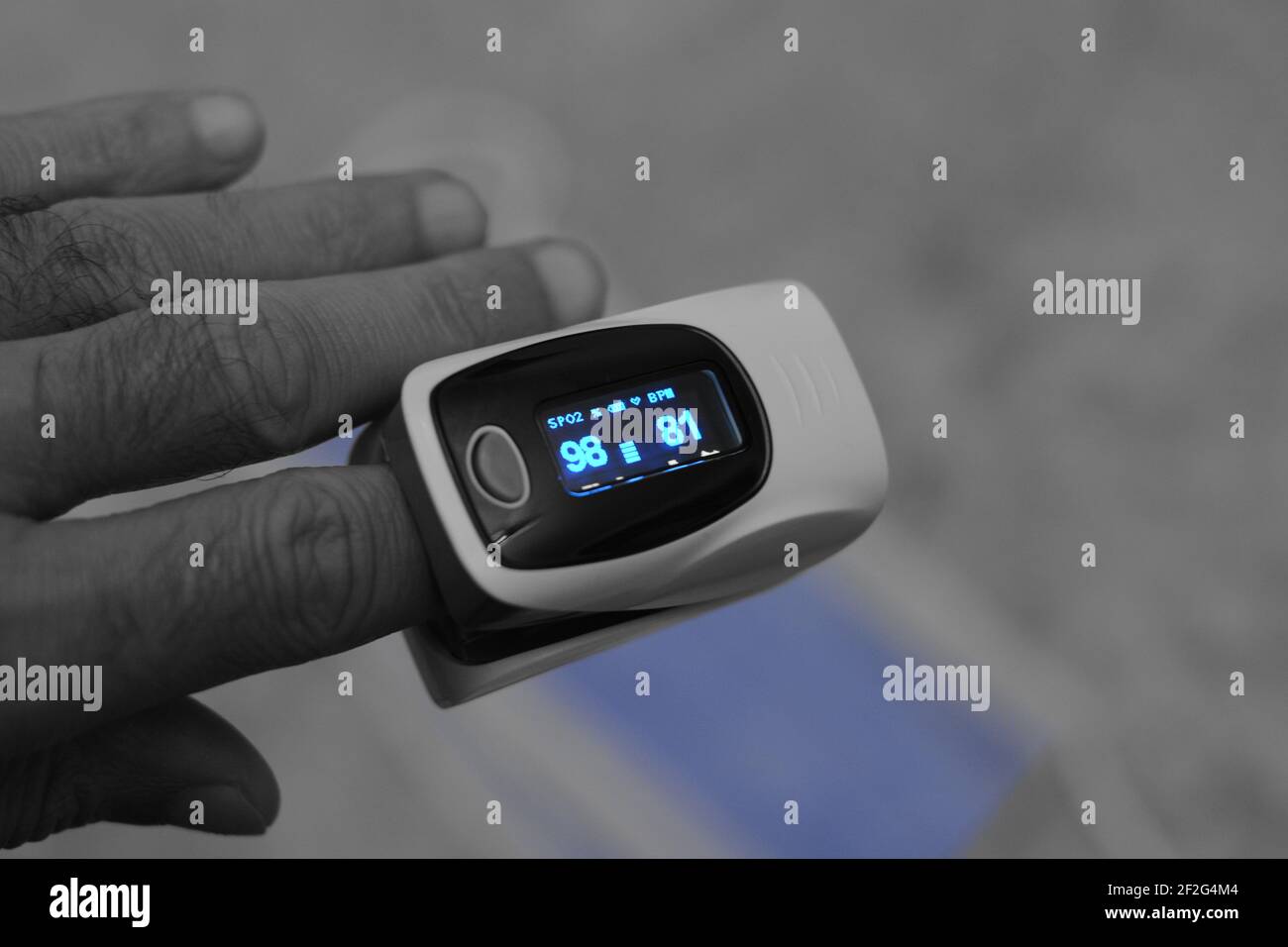 pulsossimetro fingertip collegato al dito indice di un giovane uomo che misura la saturazione di ossigeno nel sangue e la frequenza cardiaca. Foto Stock