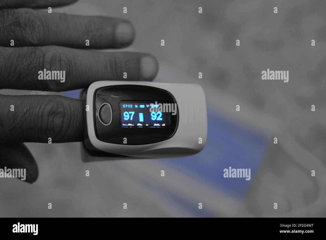 pulsossimetro fingertip collegato al dito indice di un giovane uomo che misura la saturazione di ossigeno nel sangue e la frequenza cardiaca. Foto Stock