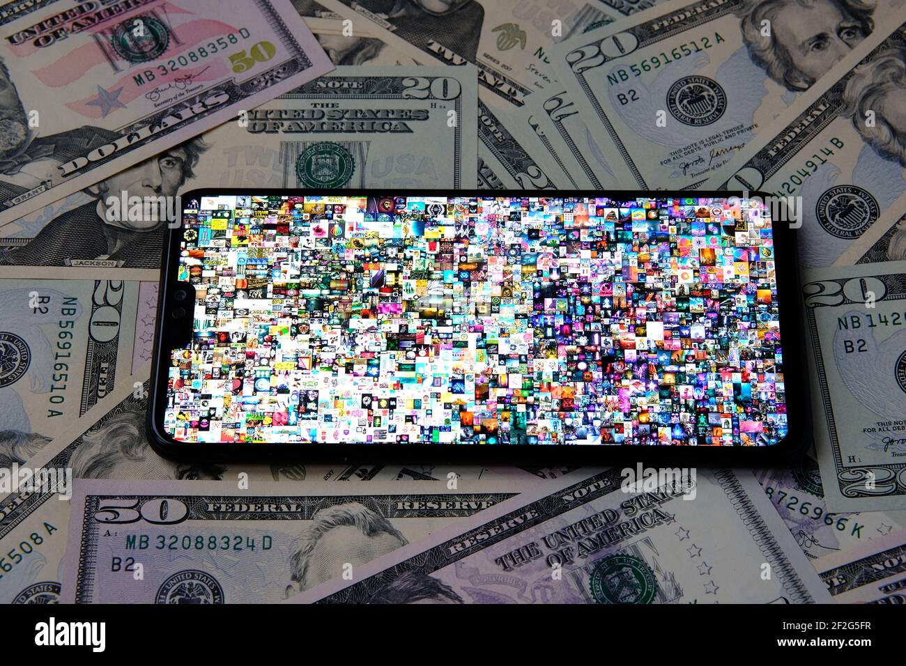 Smartphone con Beeple ' EVERYDAYS: I PRIMI 5000 GIORNI 'collage art firmato con NFT token visto sullo schermo posto sul dollaro. Concetto. Staffor Foto Stock