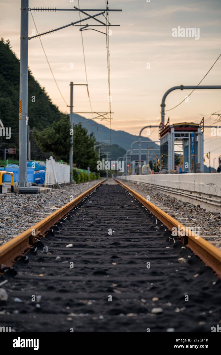 Vista ad angolo basso del binario ferroviario e del polo elettrico del collettore alla stazione Foto Stock