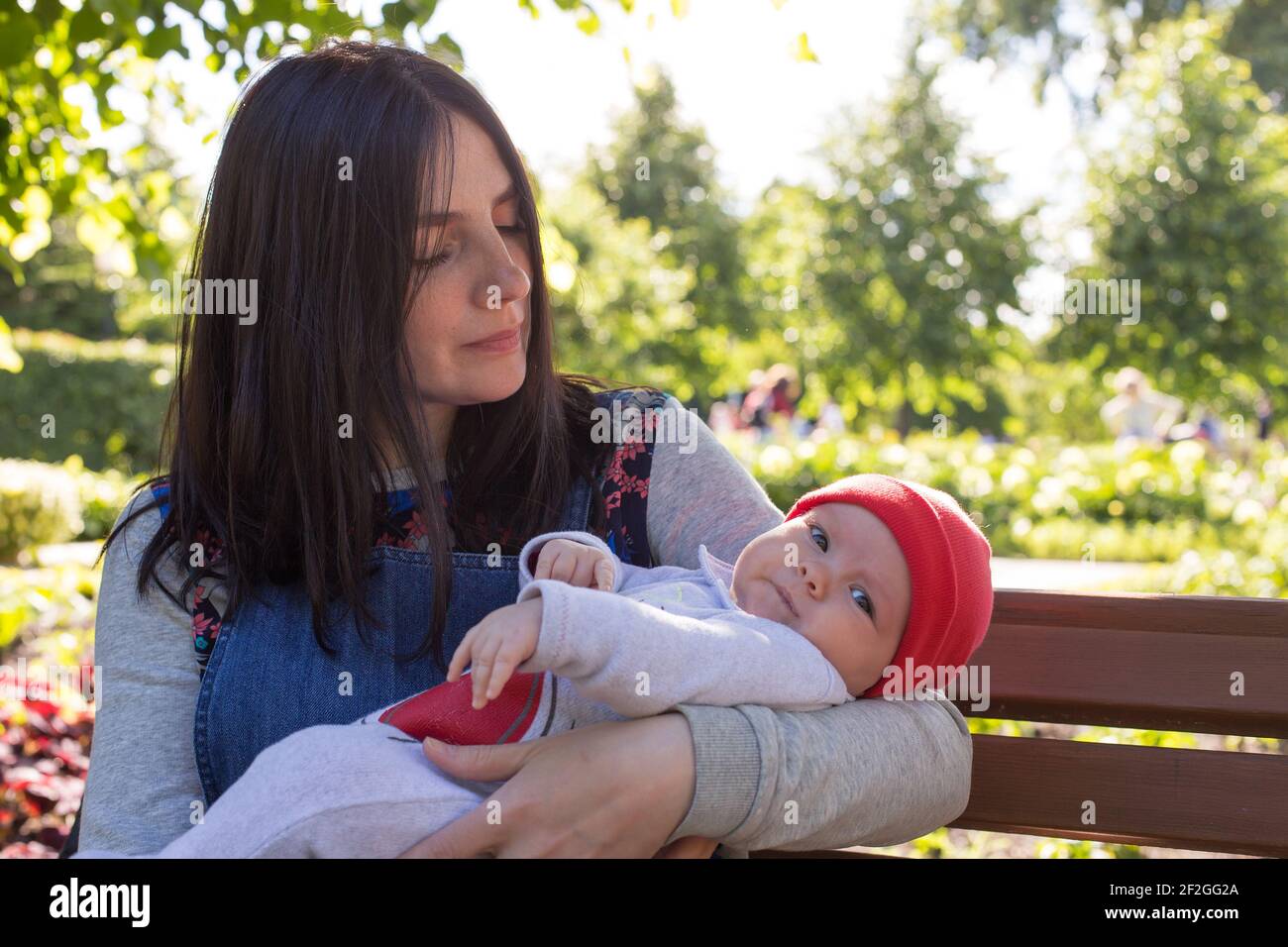 La giovane madre sta tenendo un neonato tra le braccia per una passeggiata nel parco. Messa a fuoco selettiva. Foto Stock