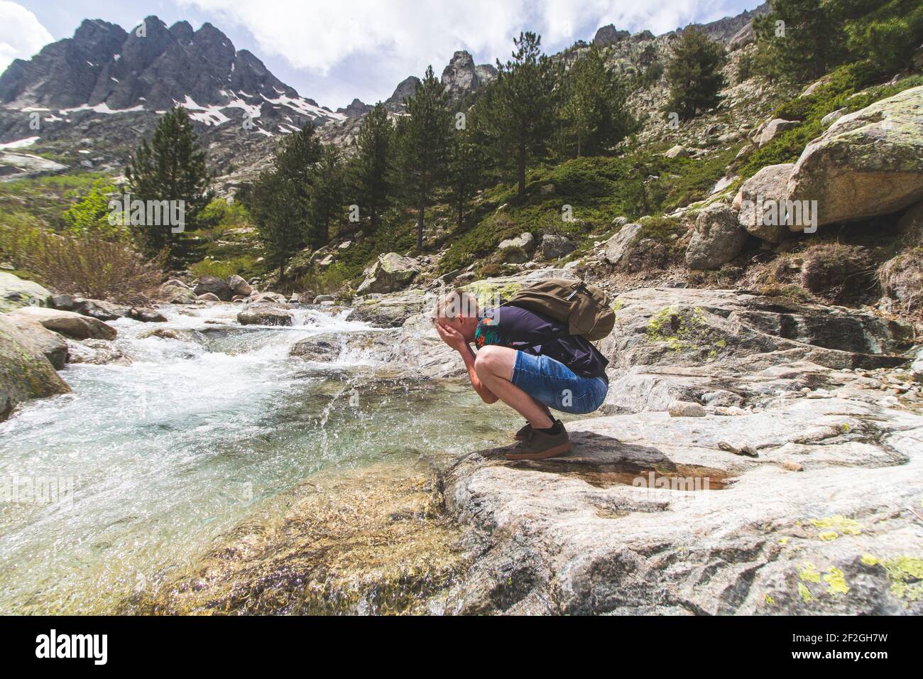 L'uomo beve acqua dalle montagne naturali fiume fresco Foto Stock