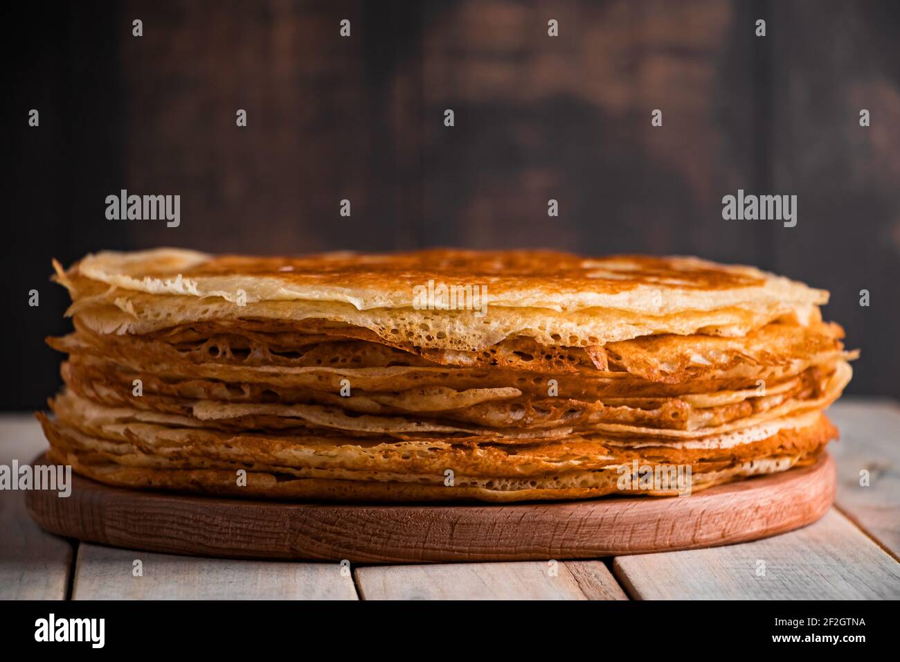 Cibo tradizionale russo - frittelle sottili. Una pila di crepes su uno sfondo di legno marrone scuro. Stile rustico, posto per il testo. Foto Stock