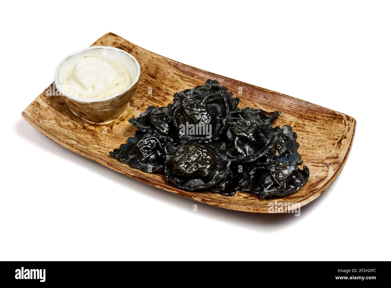 Dim sum nero su un piatto di legno su sfondo bianco. Foto Stock