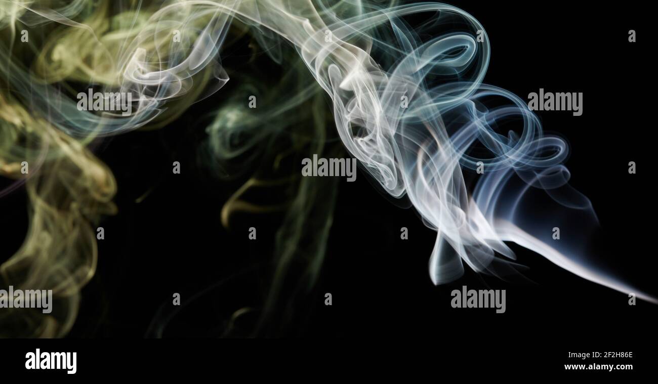 La linea di fumo gialla e blu ruota su sfondo nero isolato Foto Stock