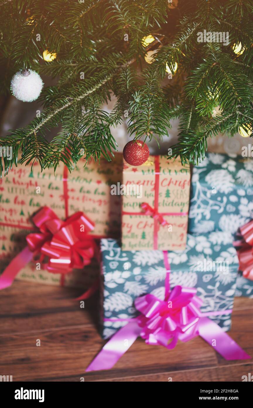 Scatole regalo con nastri sotto l'albero di Natale con luce offuscata Foto Stock
