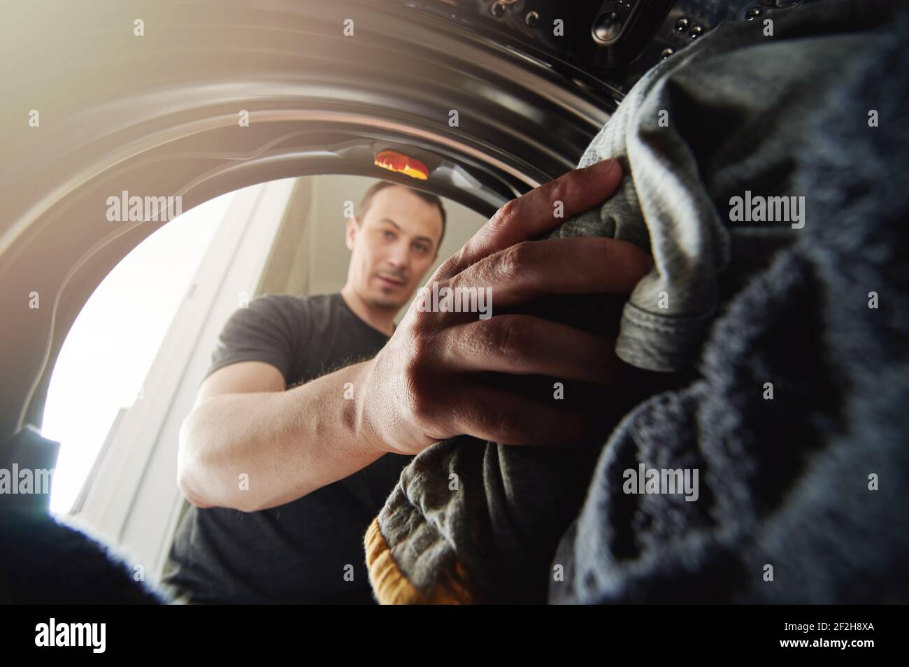 Il giovane uomo che fa il tema di lavoro domestico. Lavare i vestiti sporchi Foto Stock