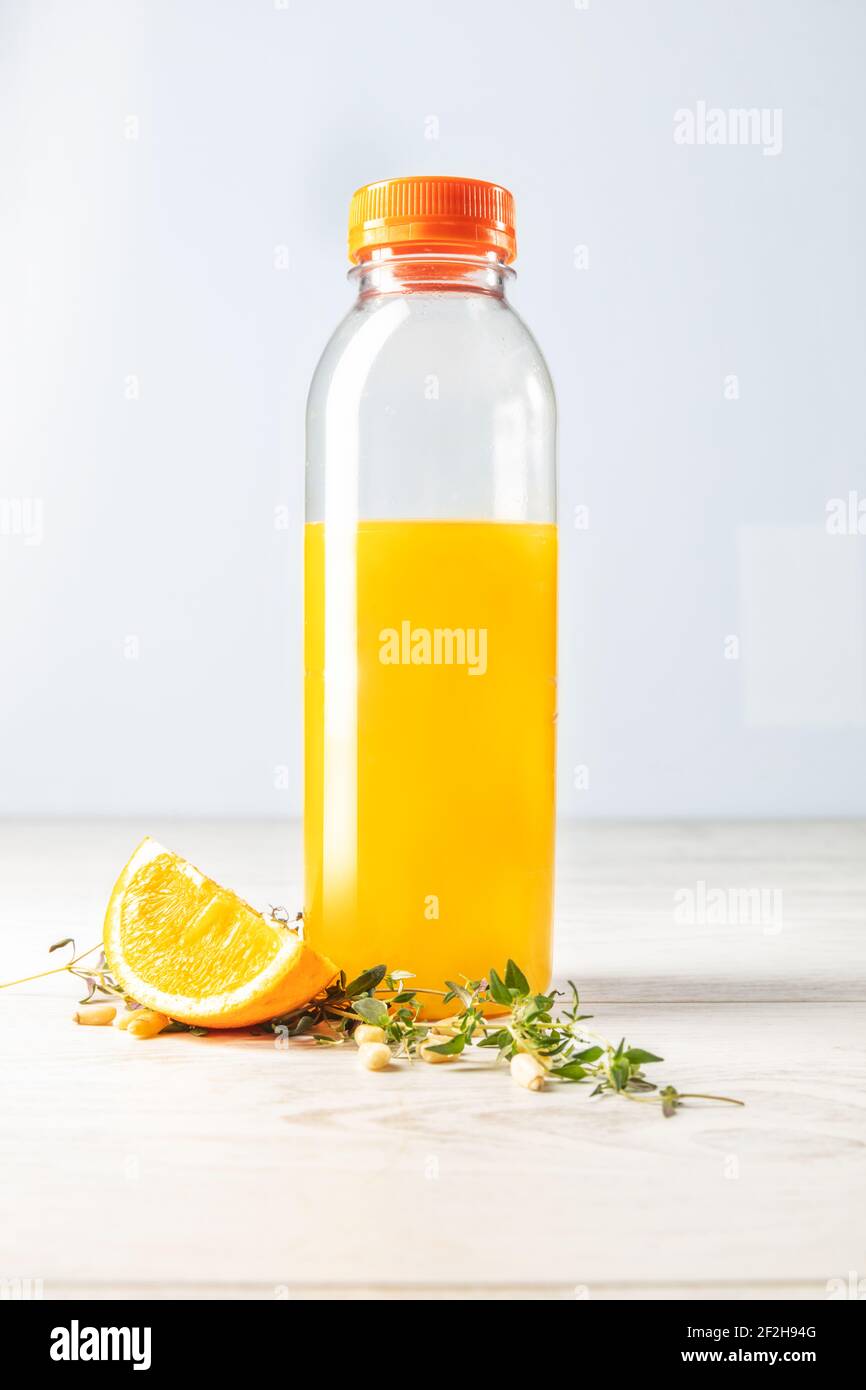 bottiglia di succo d'arancia naturale con composizione arancione su sfondo di legno chiaro vista frontale. Foto Stock