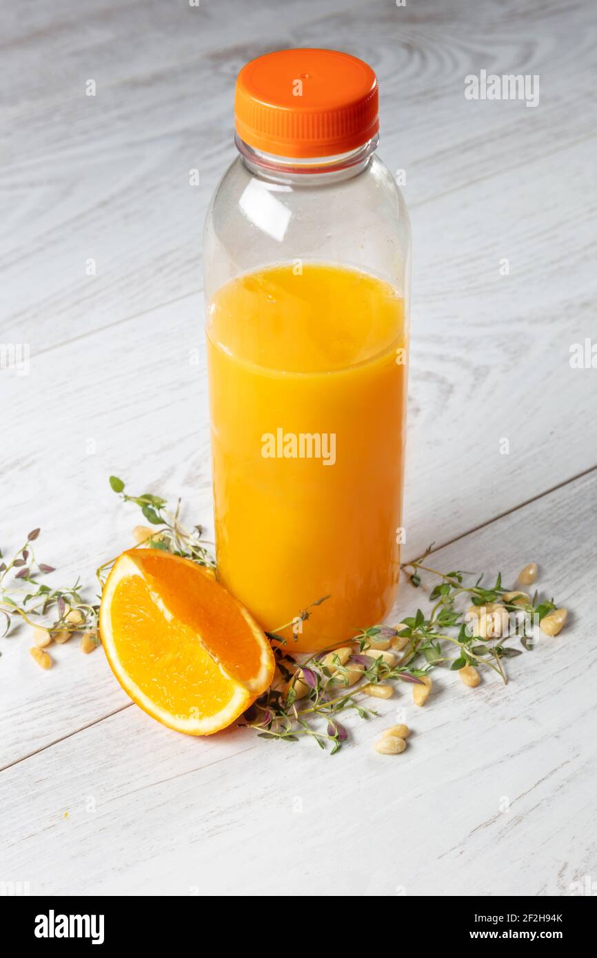 bottiglia di succo d'arancia naturale con composizione arancione su sfondo di legno chiaro visto dall'alto. Foto Stock