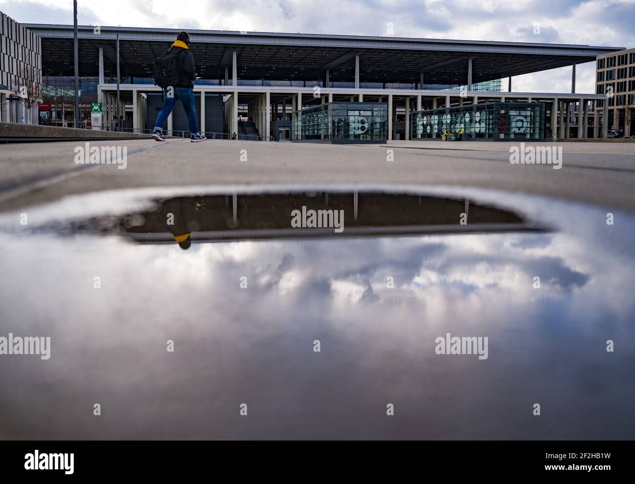 12 marzo 2021, Brandeburgo, Schönefeld: Terminal 1 dell'aeroporto della capitale Berlino il Brandeburgo "Willy Brandt" (BER) si riflette in una pozza. Nel pomeriggio si svolge una riunione del Consiglio di sorveglianza della Flughafen Berlin-Brandenburg GmbH. L'argomento principale è le future esigenze finanziarie dell'azienda. La società di gestione conta sulla riduzione parziale del debito da parte degli stati di Berlino, Brandeburgo e governo federale. Foto: Patrick Pleul/dpa-Zentralbild/ZB Foto Stock