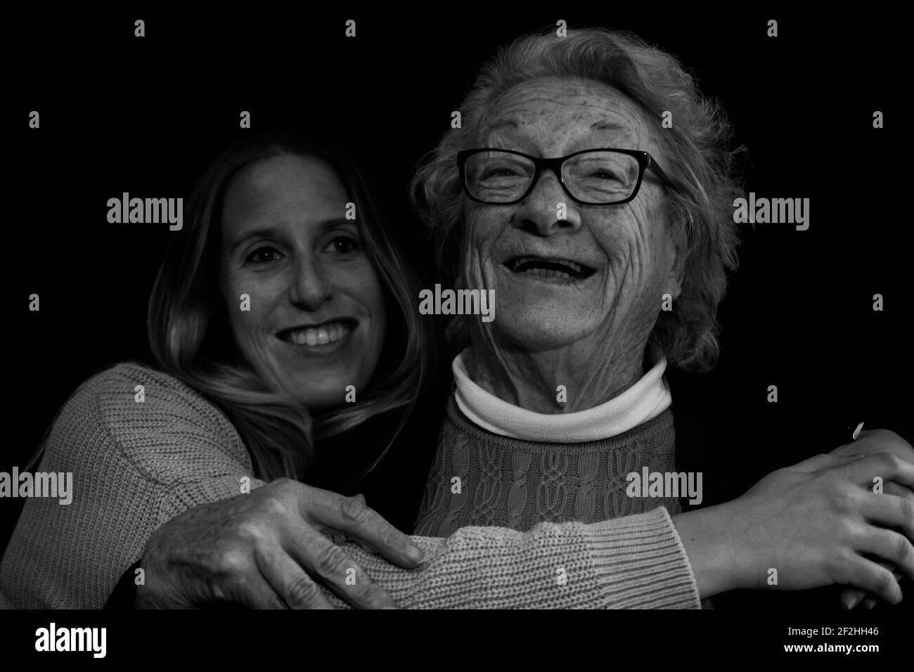 Ritratto di famiglia della donna anziana degli anni 80 abbracciando la giovane grande figlia.Fotografia in bianco e nero di persone felici sorridenti stile di vita concettuale. Foto Stock