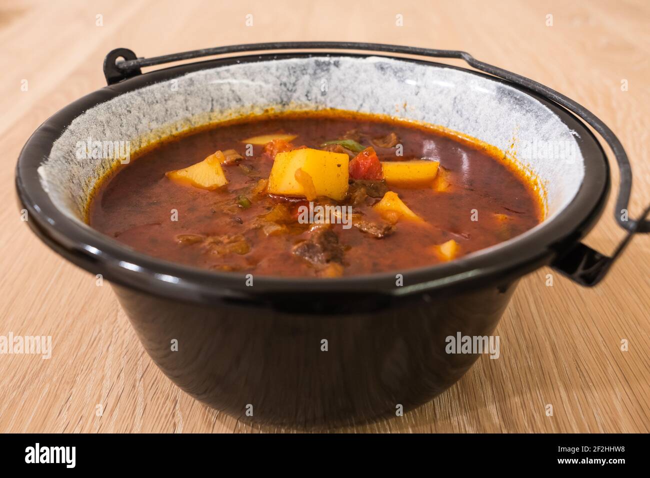 Goulash di manzo ungherese o zuppa di Gulyas o stufato serviti in un piccolo calderone con patate, carne, paprika e pepe Foto Stock