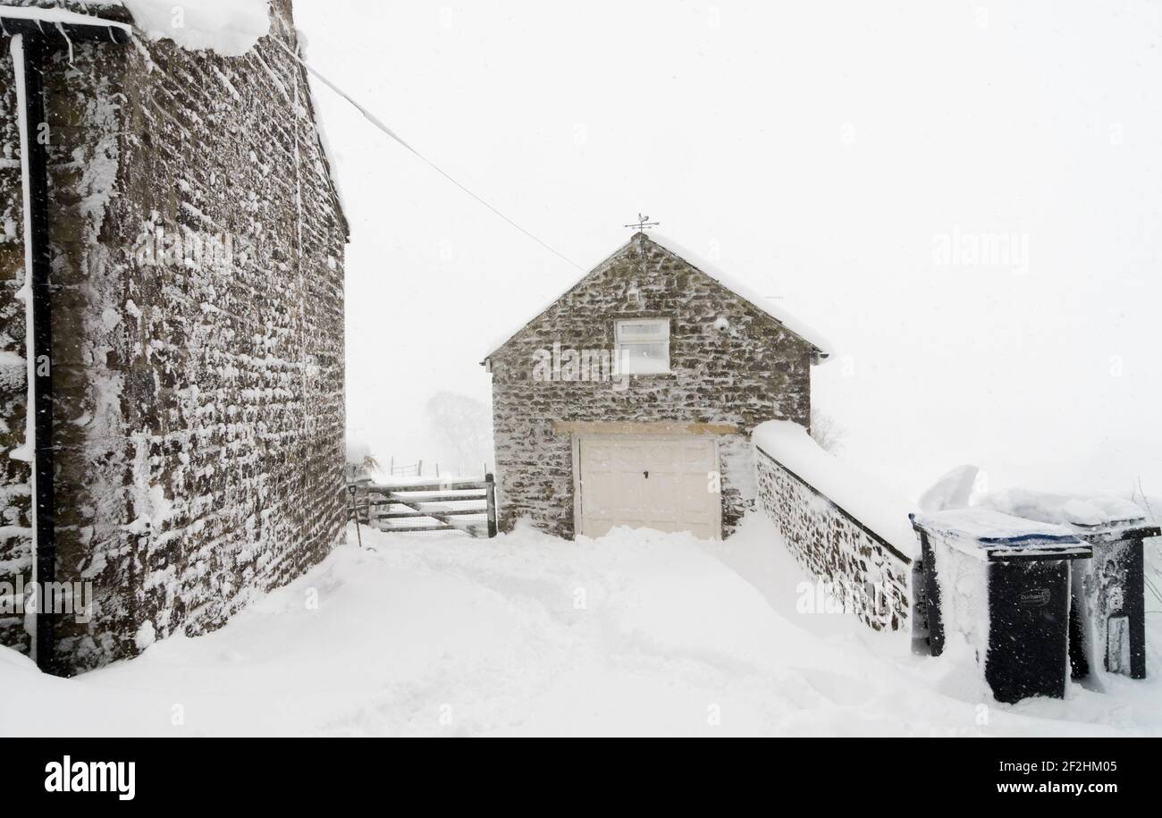 Una vecchia casa di pietra coperta di neve pesante in Weardale, il Nord Pennines, contea di Durham, Regno Unito Foto Stock