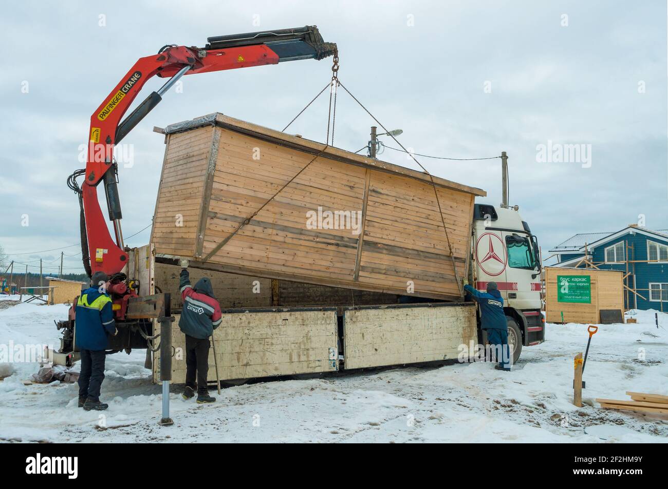 REGIONE DI LENINGRAD, RUSSIA - 04 MARZO 2021: Caricamento di una casa di costruzione su un camion Mercedes-Benz Actros con una gru manipolatrice Foto Stock