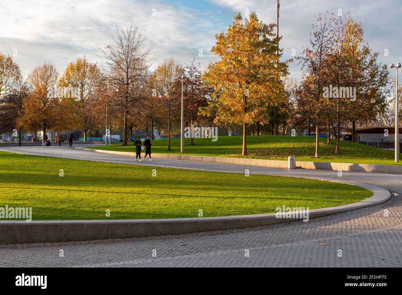 Vista al tramonto del Jubilee Park e dei giardini, con sentieri tortuosi, alberi autunnali e pedoni, South Bank, Londra Foto Stock