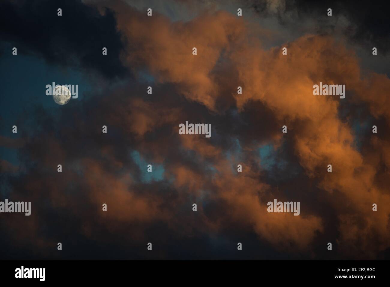 La luna tra le nuvole drammatiche al tramonto su Bonn. Foto Stock