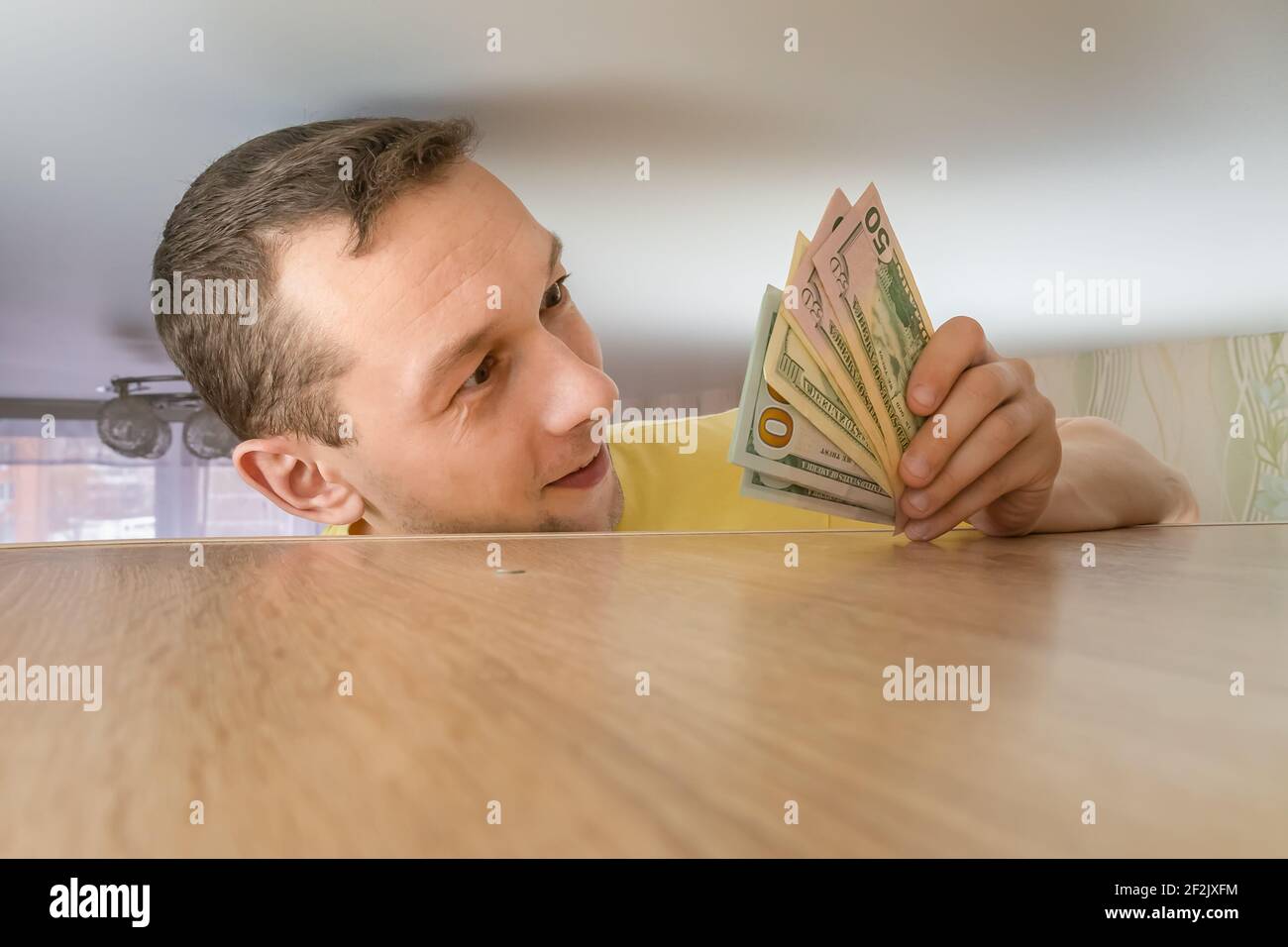 L'uomo tiene il risparmio del dollaro nascosto su un armadietto nelle sue mani. Risparmio di denaro in tempi difficili Foto Stock