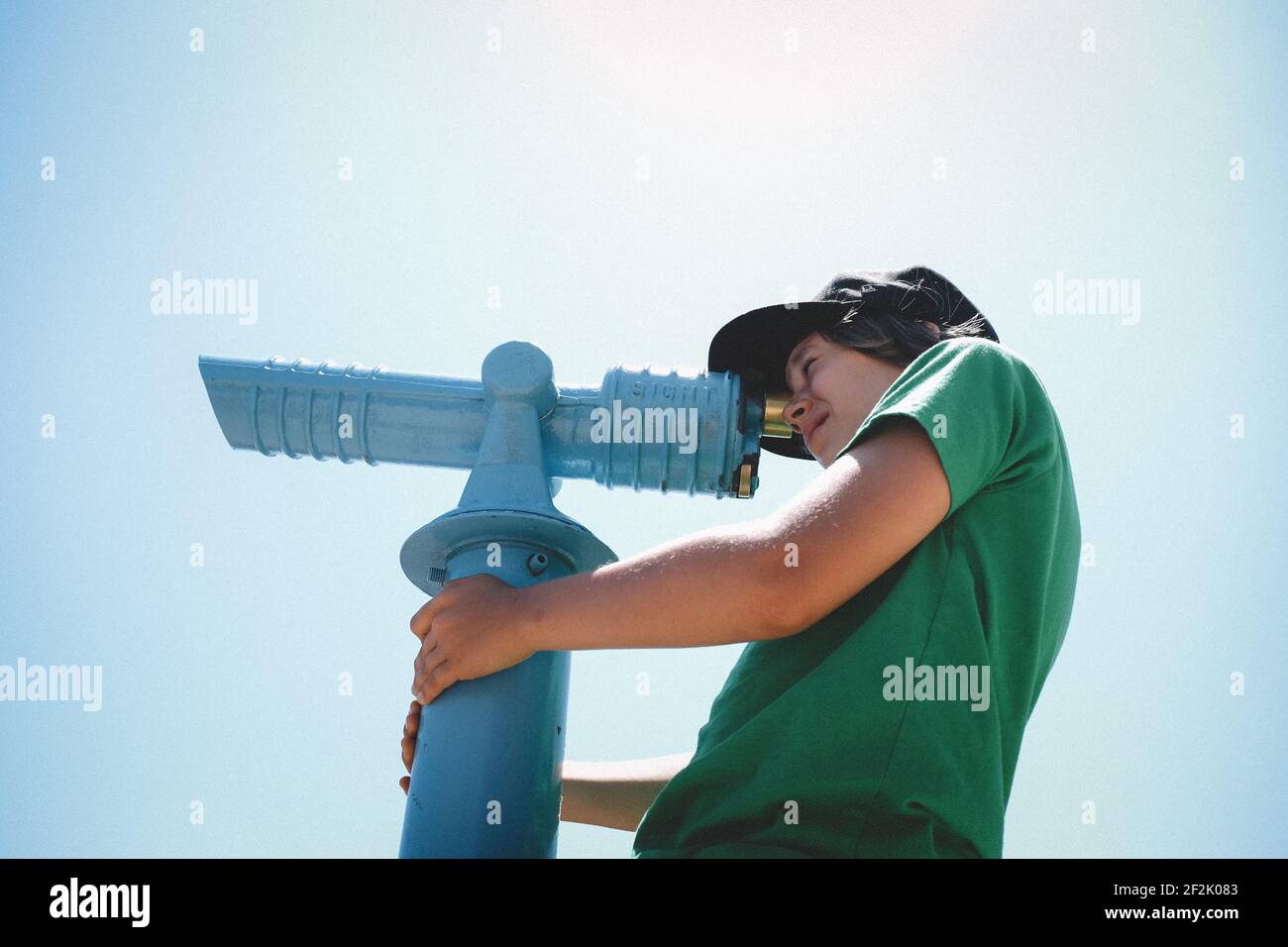 Tween Boy sbirciata attraverso Spyglass in un Blue Sky Day Foto Stock