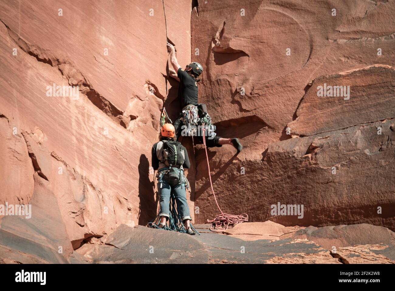 Amici maschi che arrampicano formazioni rocciose al Canyonlands National Park Foto Stock