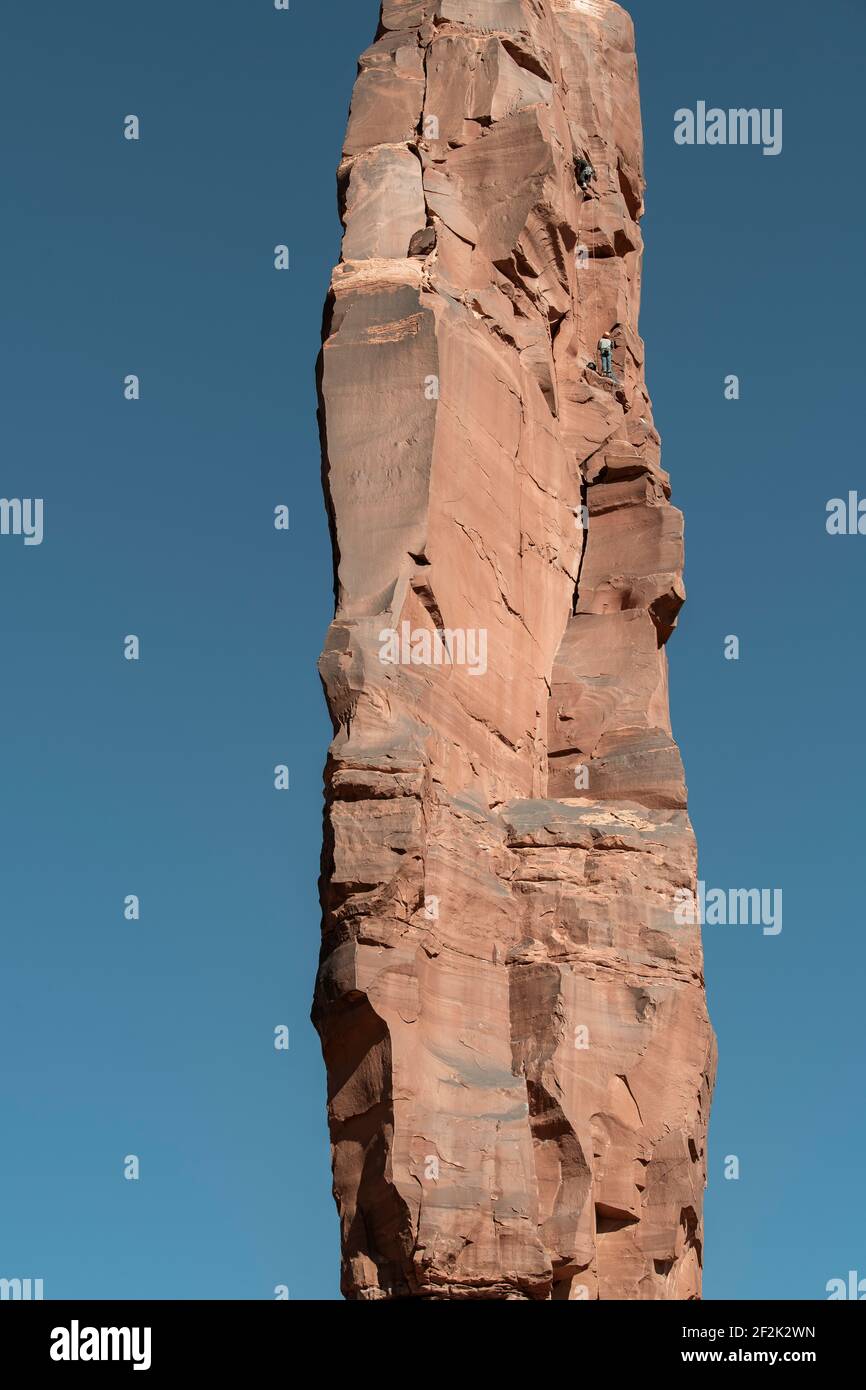 Vista a distanza degli uomini che arrampicano la formazione rocciosa contro il cielo limpido Al Canyonlands National Park Foto Stock