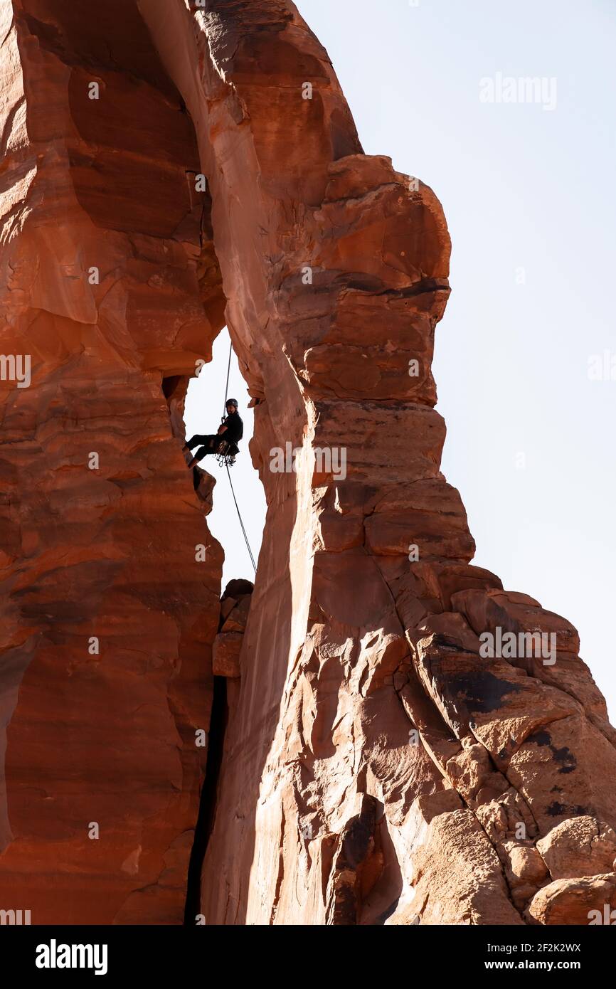 Vista ad angolo basso dell'uomo che sale su formazioni rocciose Cielo limpido al Canyonlands National Park Foto Stock