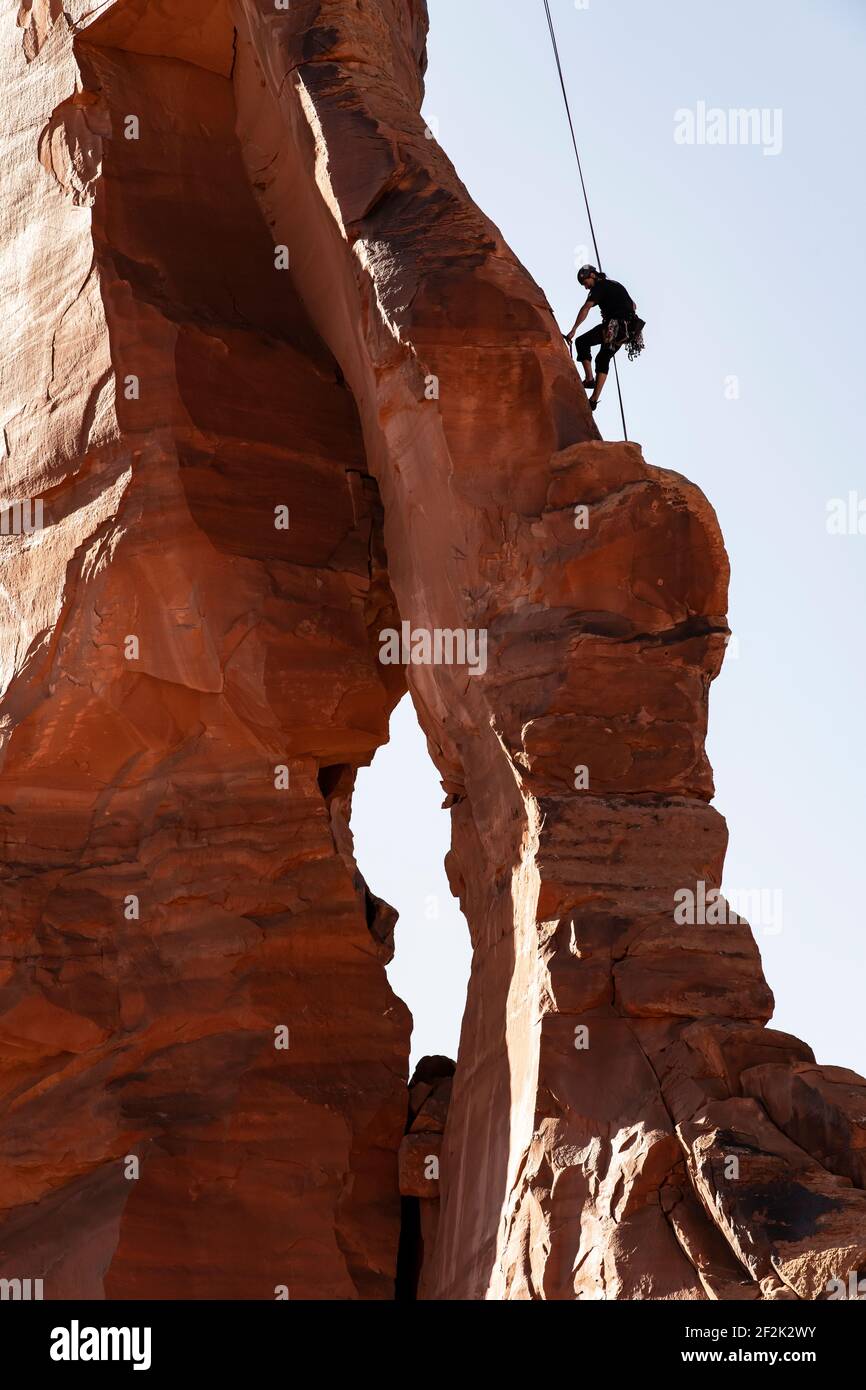Vista ad angolo basso dell'uomo che sale su formazioni rocciose Cielo limpido al Canyonlands National Park Foto Stock