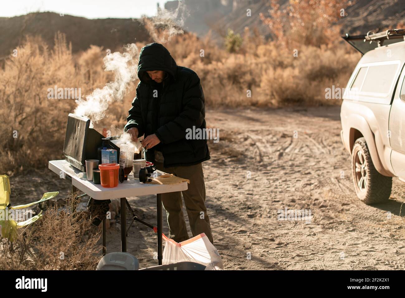 Uomo che prepara il caffè sulla stufa da campeggio durante l'esplorazione Canyonlands National Parcheggia durante le vacanze Foto Stock