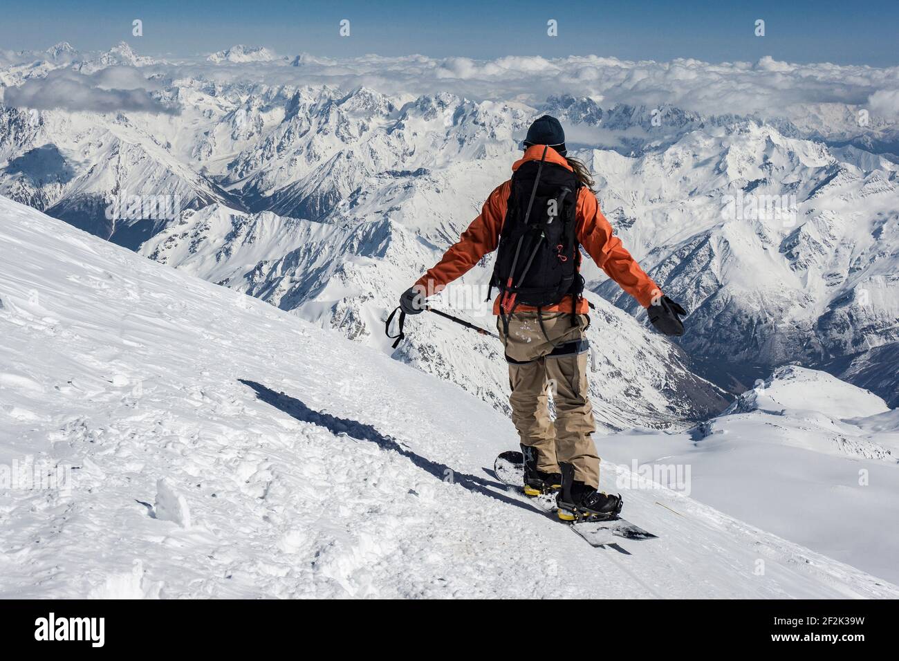 Vista posteriore dell'uomo in piedi con le braccia distese su innevato montagna durante le vacanze Foto Stock