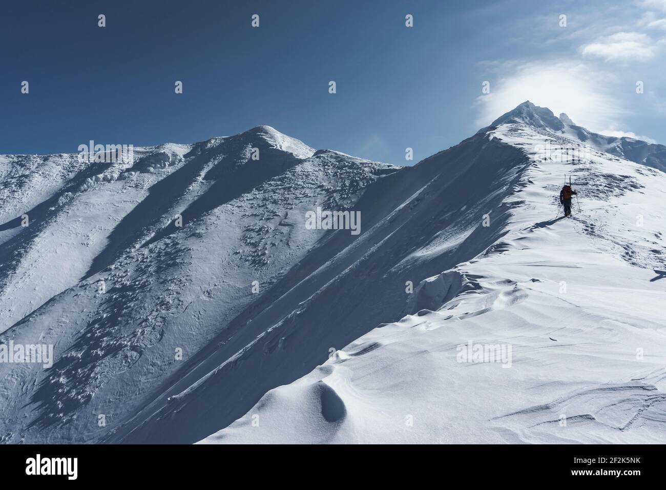 Vista dall'angolo basso dell'uomo sulla montagna innevata contro il cielo Foto Stock