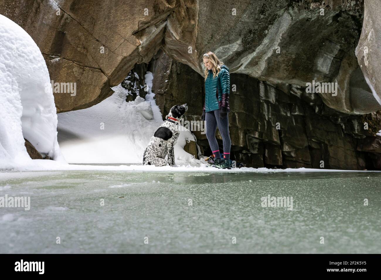 Giovane donna sorridente con cane in grotta durante l'inverno Foto Stock