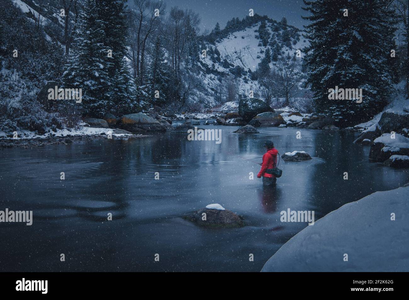 Donna pesca a mosca nel fiume durante la nevicata Foto Stock