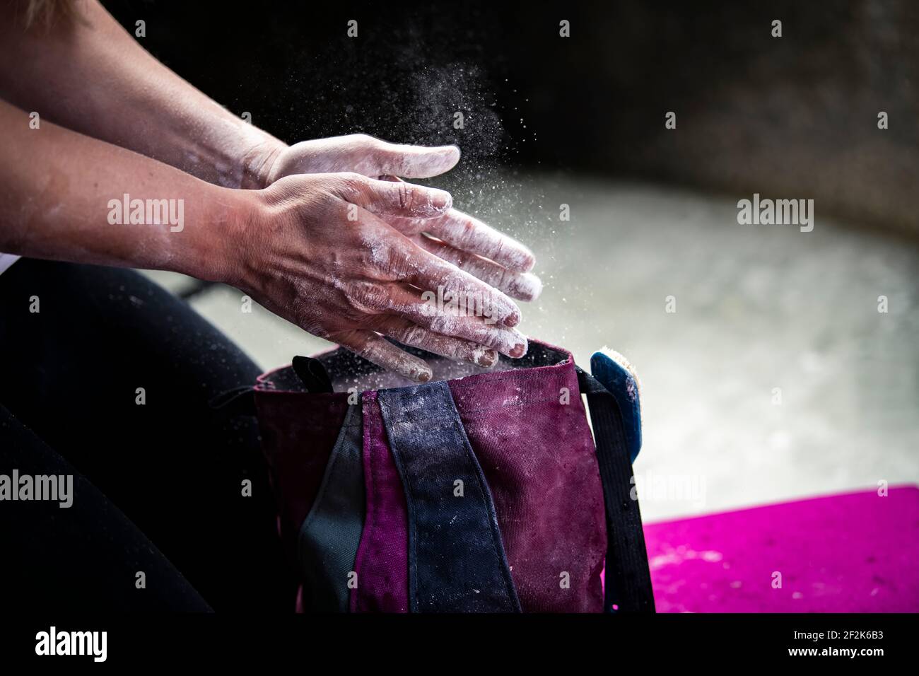 Immagine tagliata di donna che applica la polvere di gesso sulle mani prima bouldering Foto Stock