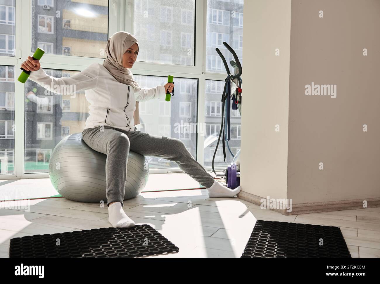 Bella donna musulmana in hijab che lavora a casa. Stile di vita sano. Allenamento domestico. Foto Stock