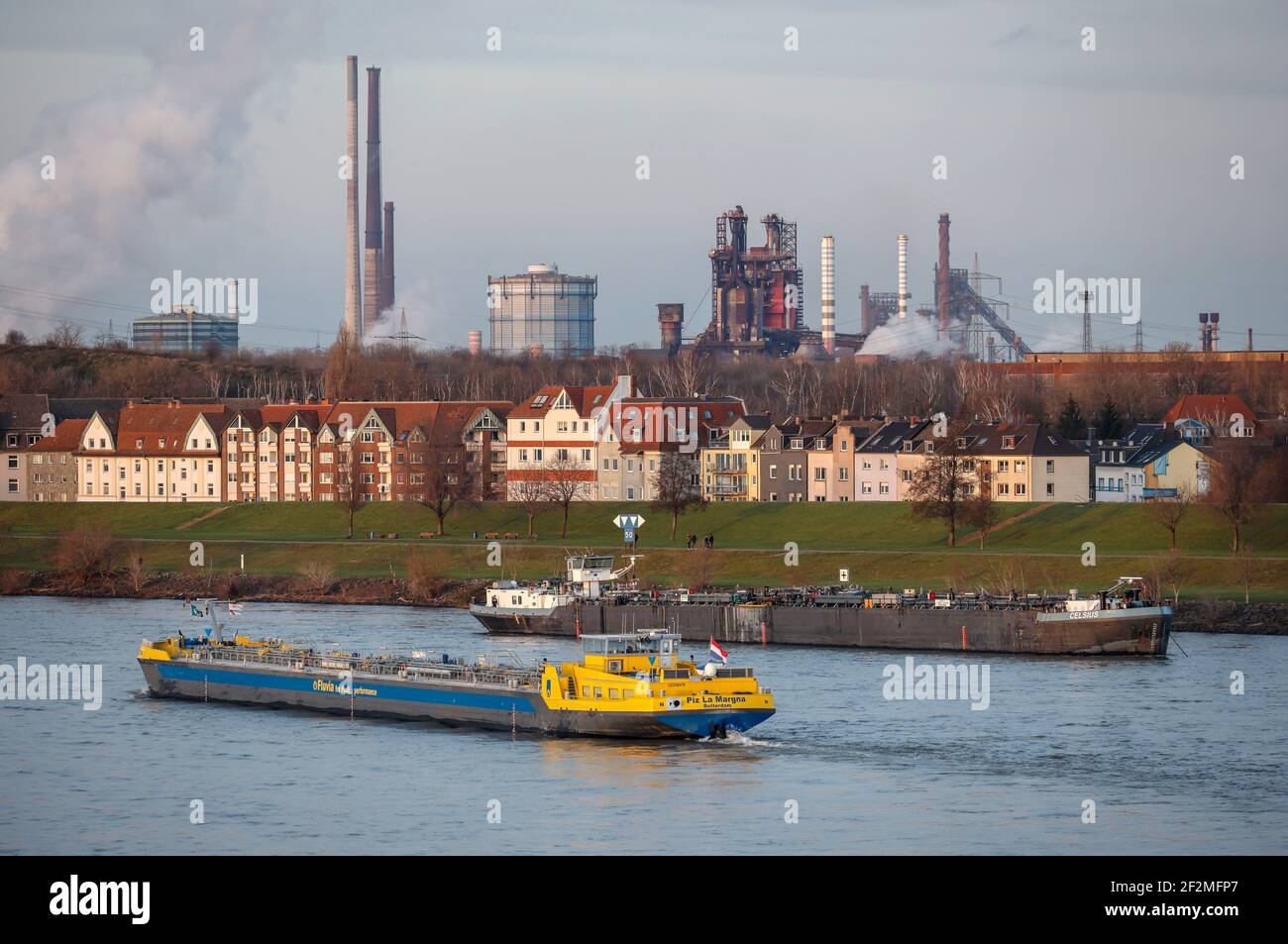 Duisburg, Renania Settentrionale-Vestfalia, Germania - paesaggio urbano nella zona della Ruhr con una nave da carico sul Reno di fronte a edifici residenziali nel distretto di Laar e sul retro l'altoforno 8 da ThyssenKrupp Huettenwerk a Brukhausen. Foto Stock