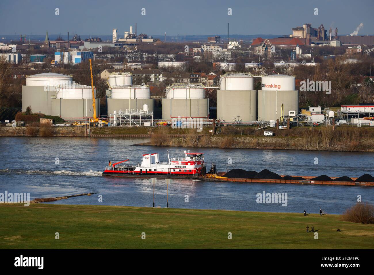 Duisburg, Ruhr, Renania Settentrionale-Vestfalia, Germania - porti di Duisburg, escursionisti sui prati del Reno Rheinhausen, nave da carico sul Reno, nel parco di Oiltanking Deutschland GmbH, grandi serbatoi per biocarburanti e oli vegetali al porto parallelo di Duisburg Neuenkamp. Foto Stock
