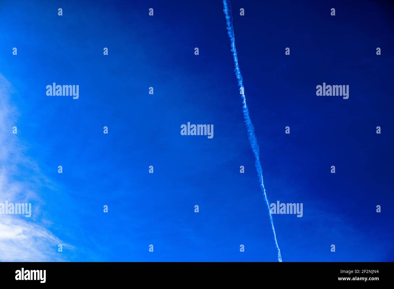 Cielo blu con piste di condensazione di un aereo Foto Stock