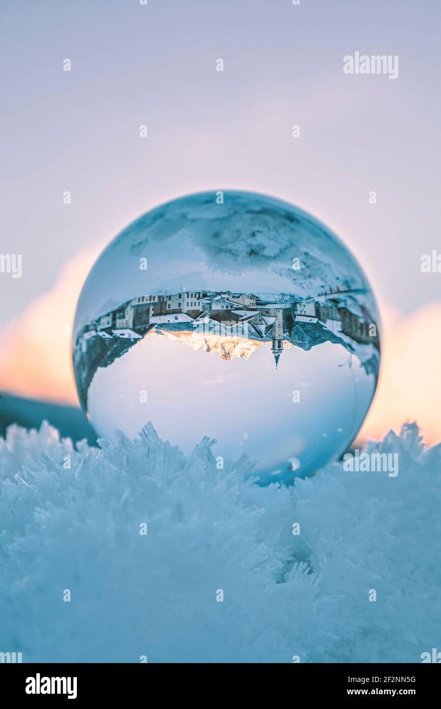 l'antico borgo di vinigo visto attraverso una palla di cristallo che riposa sulla neve ghiacciata. Borca di cadore, provincia di belluno, dolomiti, veneto, italia Foto Stock