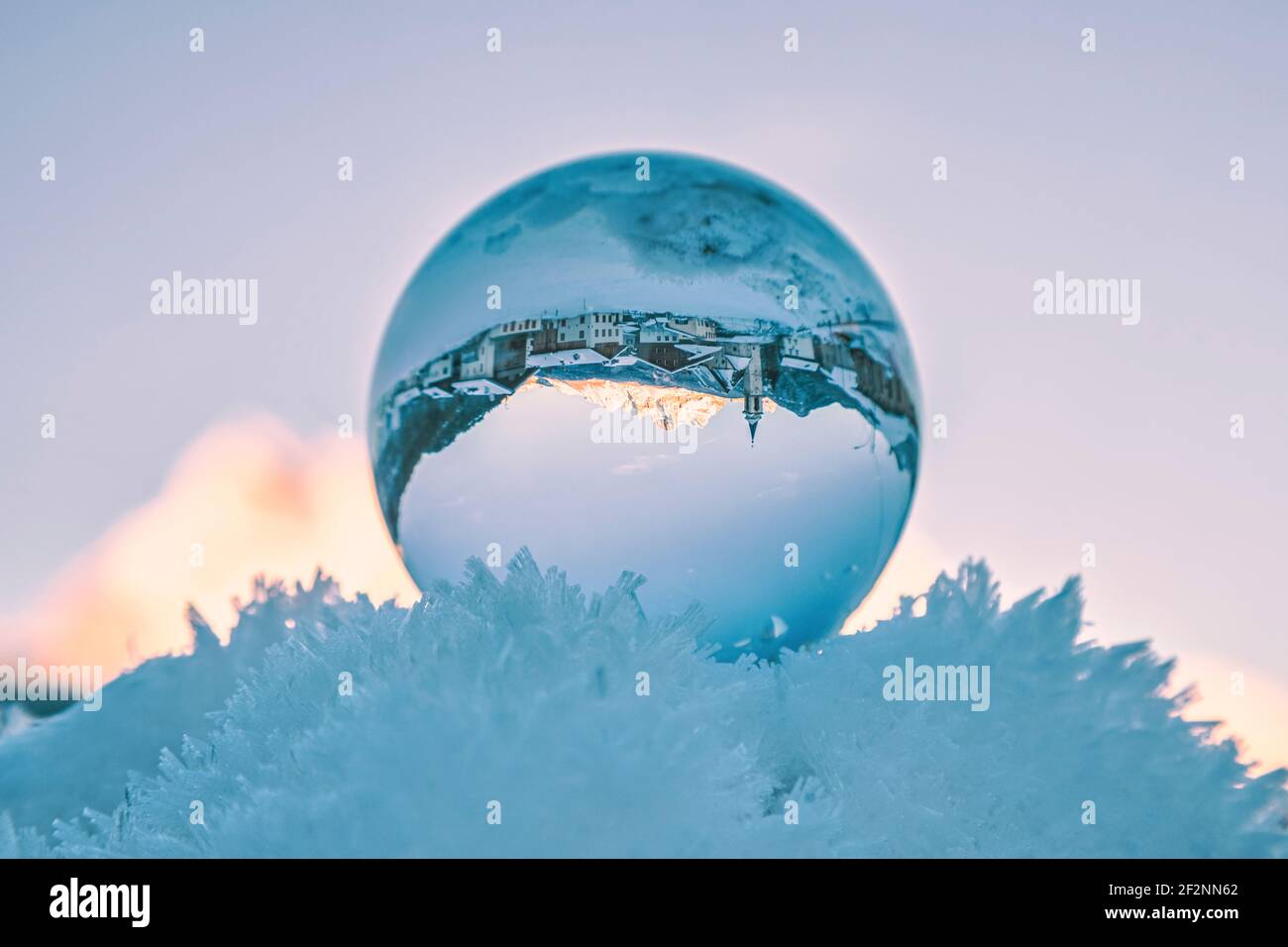 l'antico borgo di vinigo visto attraverso una palla di cristallo che riposa sulla neve ghiacciata. Borca di cadore, provincia di belluno, dolomiti, veneto, italia Foto Stock