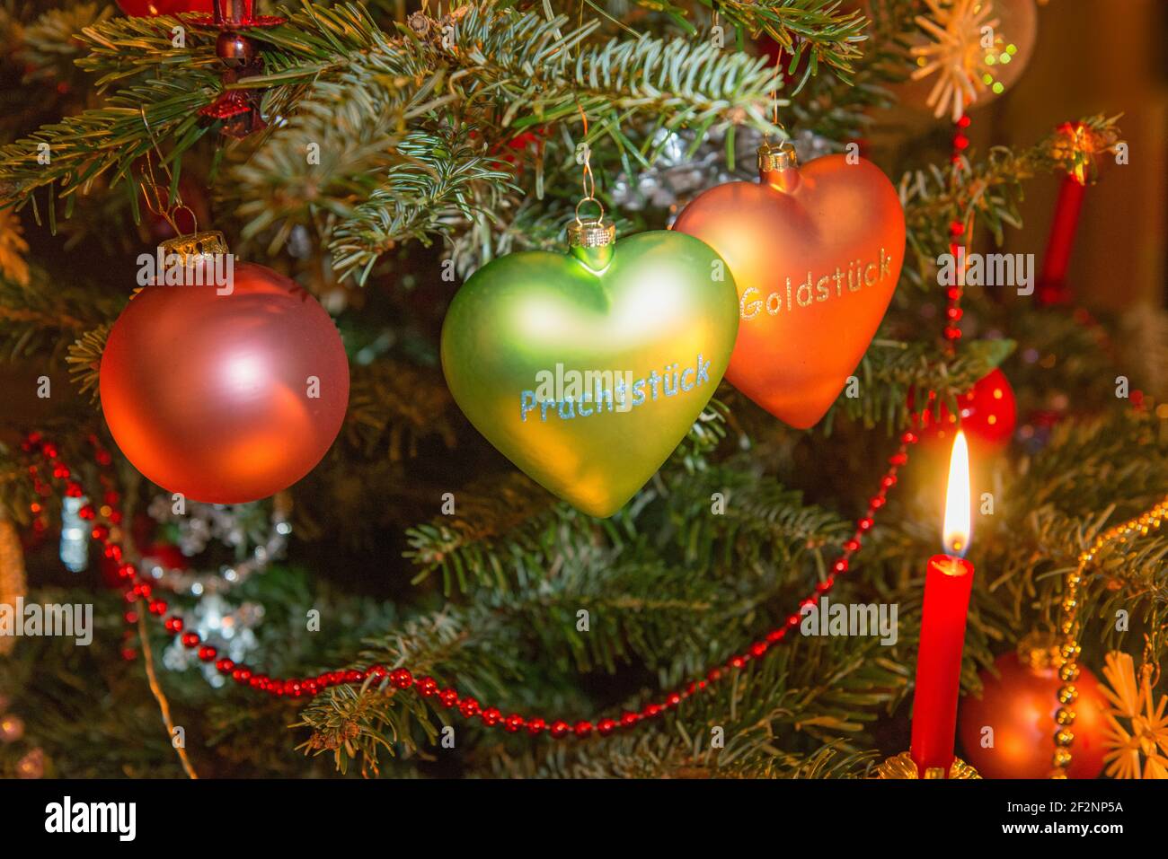 Decorazioni dell'albero di Natale, palle di vetro, cuori di vetro, candele brucianti, gemme, pezzi d'oro Foto Stock