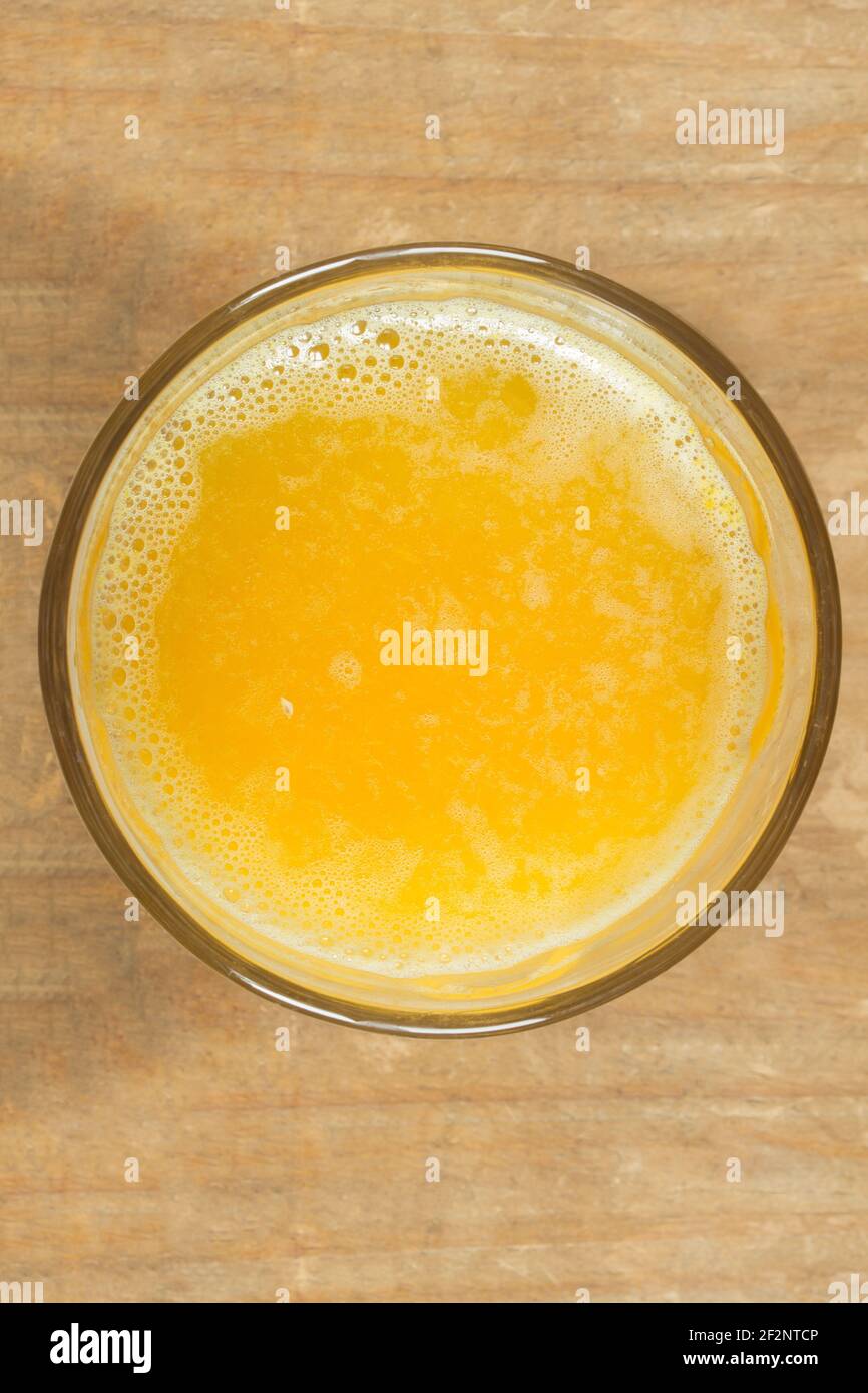 Vista dall'alto di un bicchiere pieno di succo d'arancia spremuto su un tavolo di legno. Bevande, frutta e succhi sani. Foto Stock