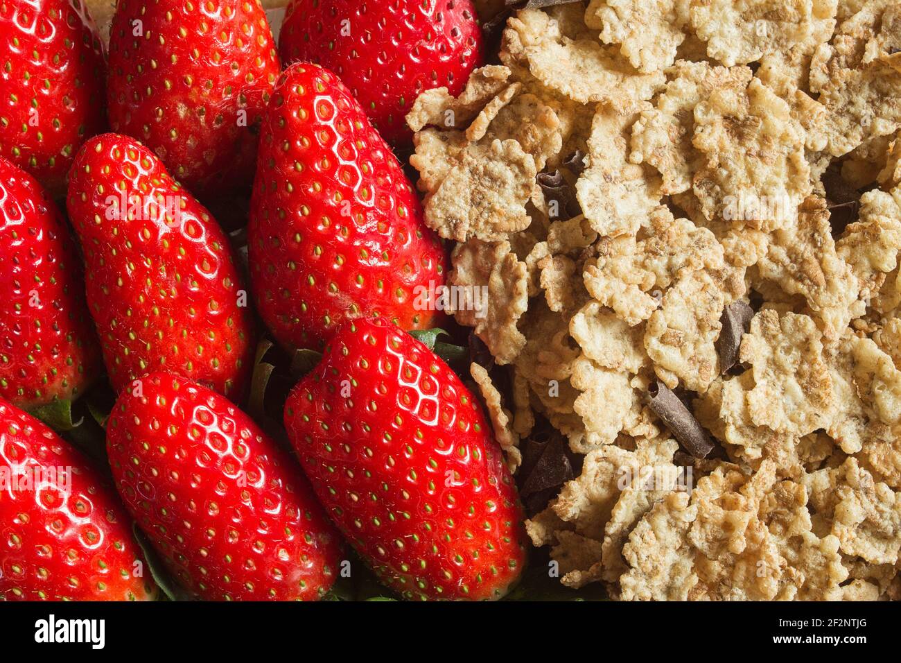 Primo piano di fragole e cereali di grano intero con cioccolato fondente. Tessuti e sfondi sani. Foto Stock