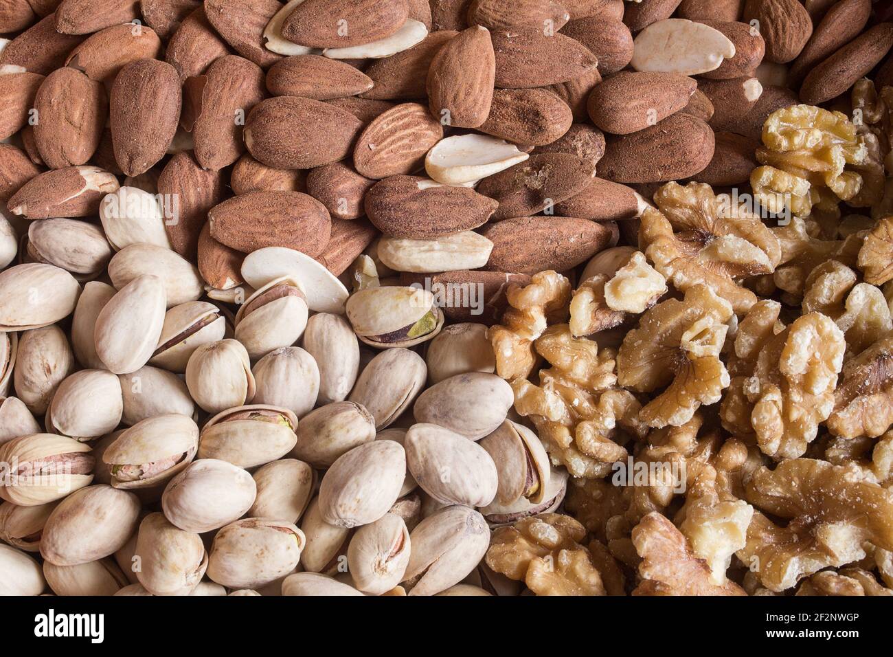 Un triangolo alimentare composto da mandorle, pistacchi e noci. Fondi, cibo e salute. Foto Stock