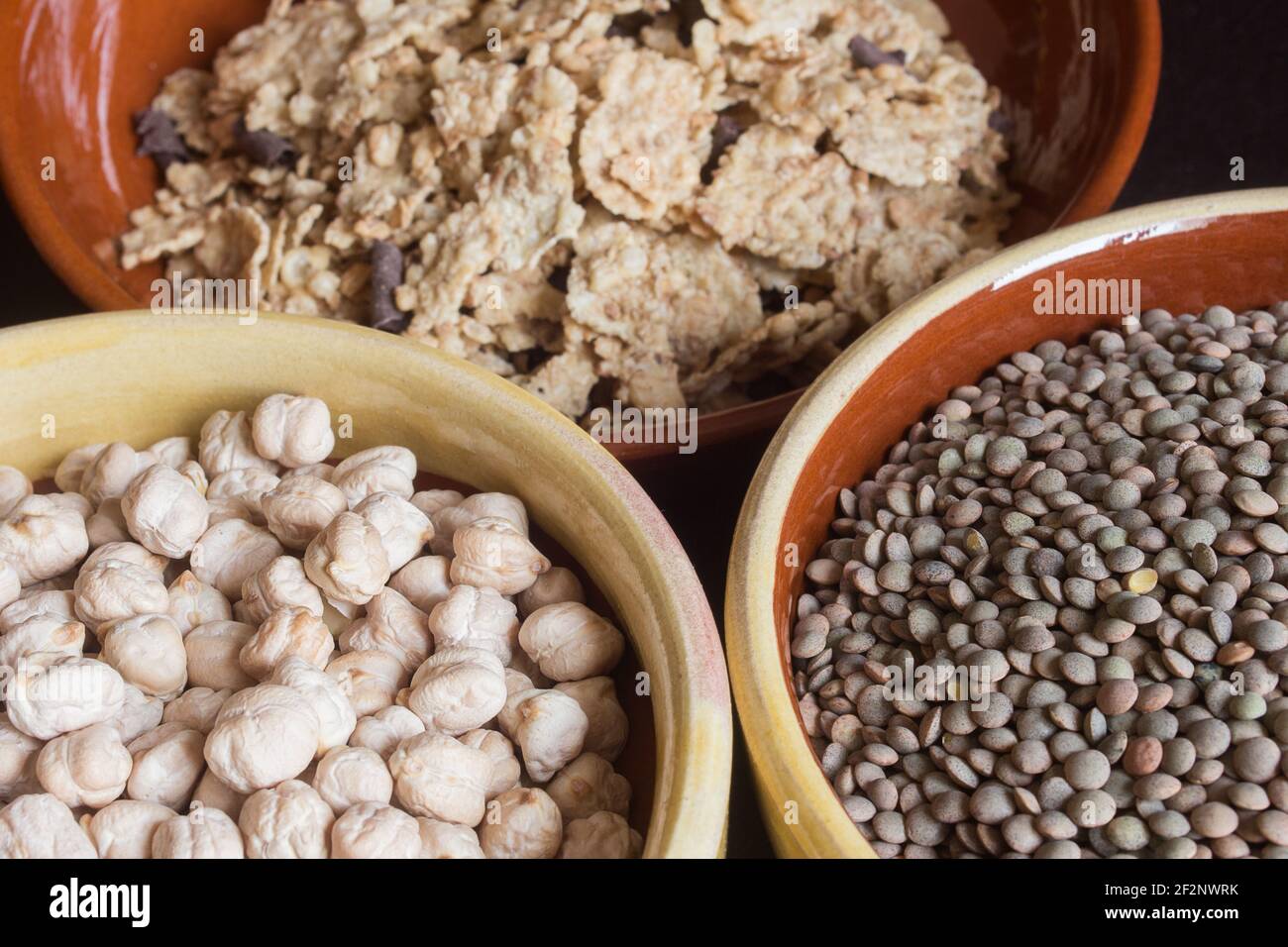 Primo piano di una ciotola di ceci, un'altra di lenticchie con uno sfondo poco focalizzato di cereali. Foto Stock